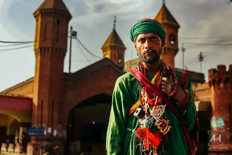 A man in a green turban and prayer beads outside Lahore railway station