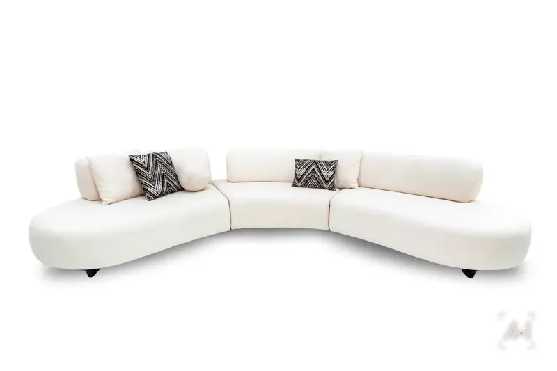 A curved three-piece cream bouclé sofa with chevron cushions
