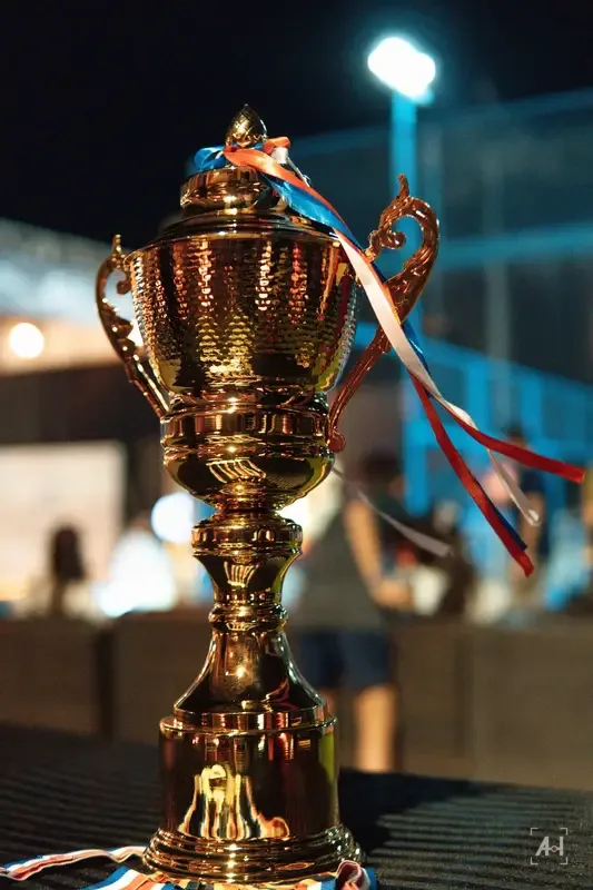 The gold trophy with ribbons under the floodlights at Club Padel