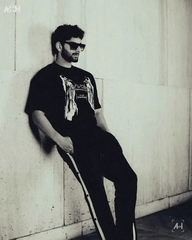 A Baaghi graphic tee in black and white, model leaning on a wall
