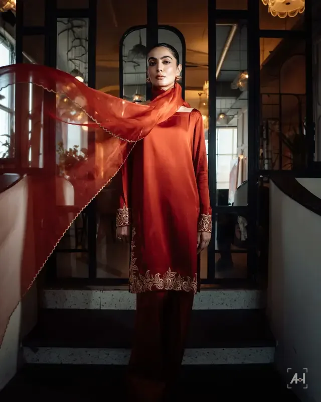 A rust KTF outfit with a sheer dupatta caught mid-throw