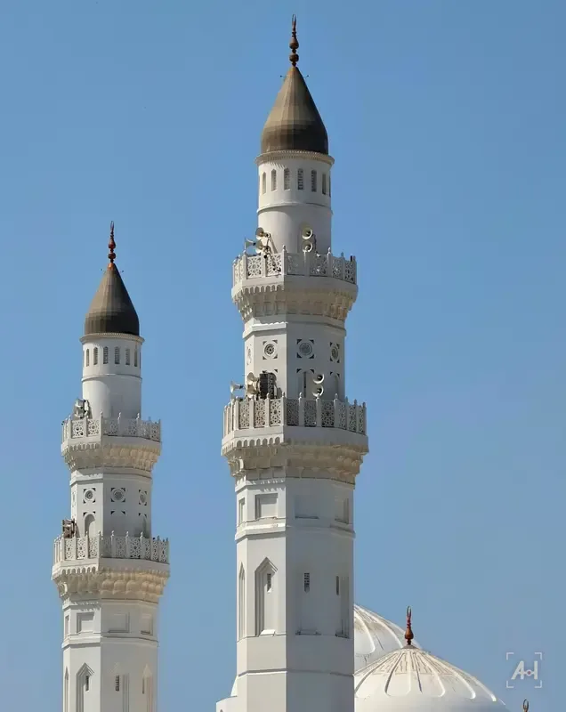The white minarets of Quba Mosque against a deep blue sky