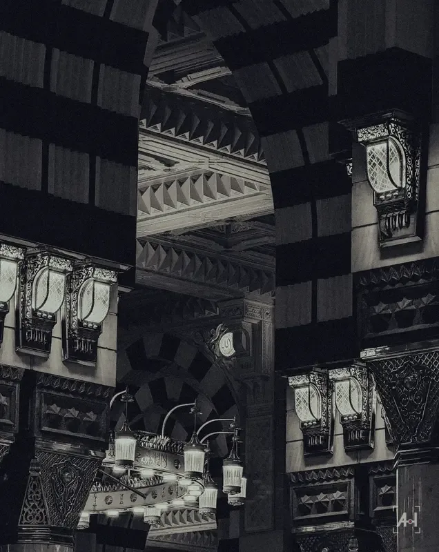 Lanterns and a chandelier among the arches inside the mosque, in black and white
