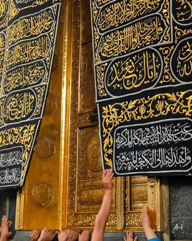 Hands reaching up to the gold door of the Kaaba beneath the embroidered kiswa