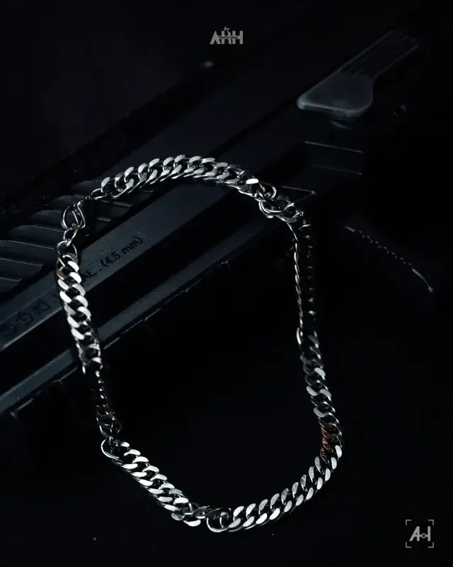 A steel curb chain draped over a black pistol grip