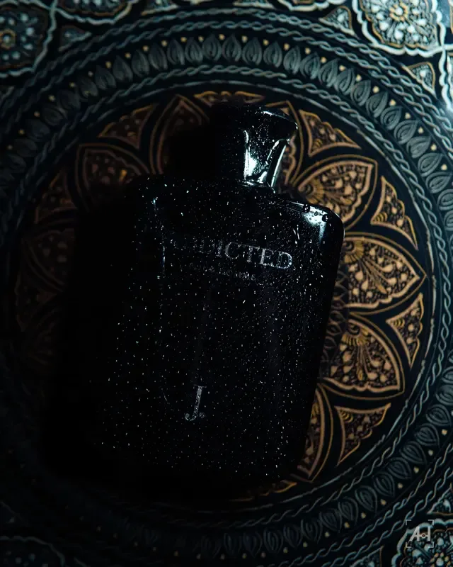 A wet black Addicted bottle on an engraved brass tray
