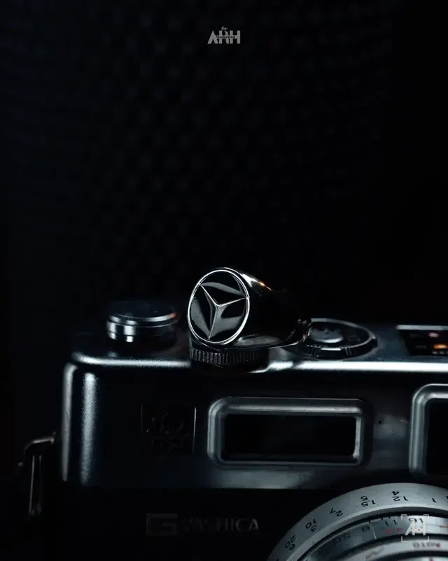 A Mercedes-star signet ring on top of a vintage Yashica rangefinder