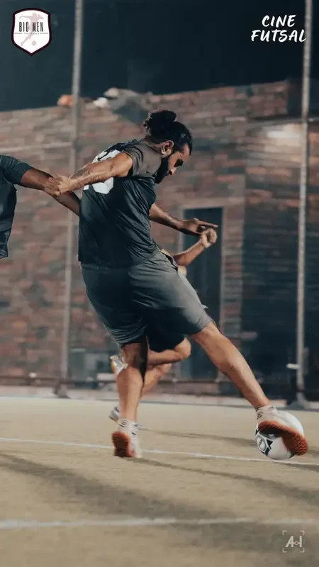 A striker swinging through a shot in front of an old brick wall