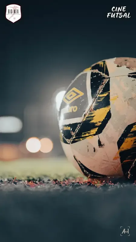 A scuffed Umbro futsal ball on the turf, floodlights blurred behind
