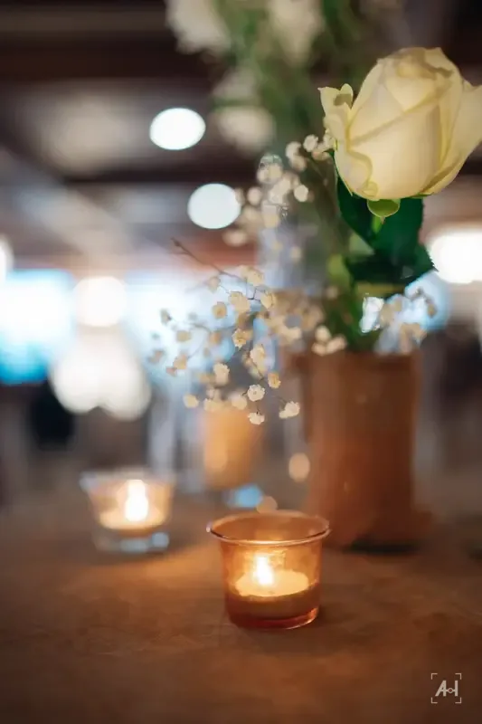 A white rose and candles on the wedding table