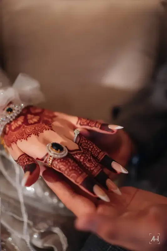 Henna-patterned hands holding the groom's