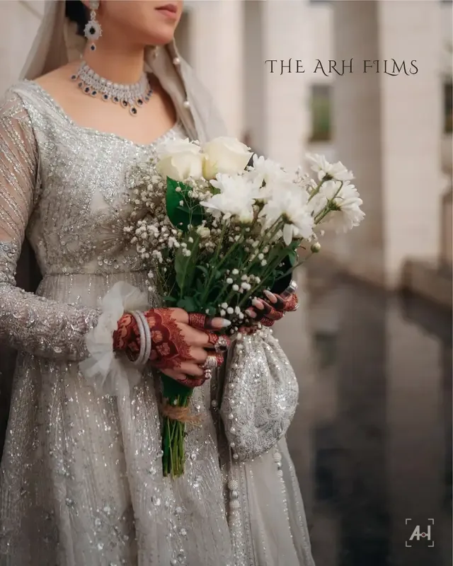 A bride in silver holding white roses