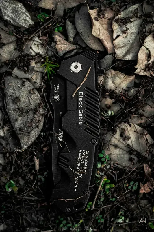 A black folding knife lying on dry leaves and soil