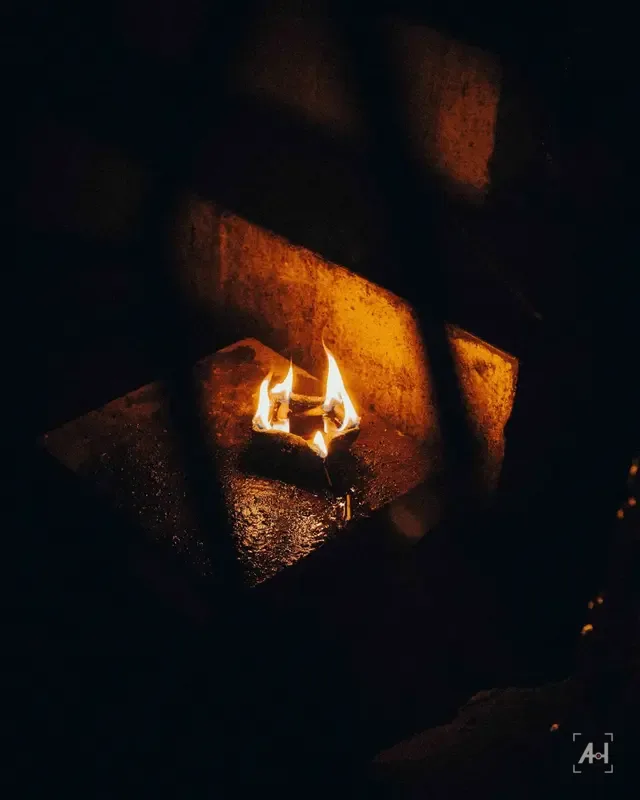 A small fire burning in a stone niche in the dark